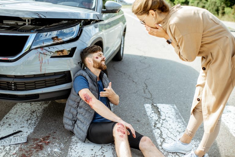 Injured man sitting on the road after a collision, highlighting the need for Motor Vehicle Accident Physiotherapy Camrose to support recovery from accident-related injuries.